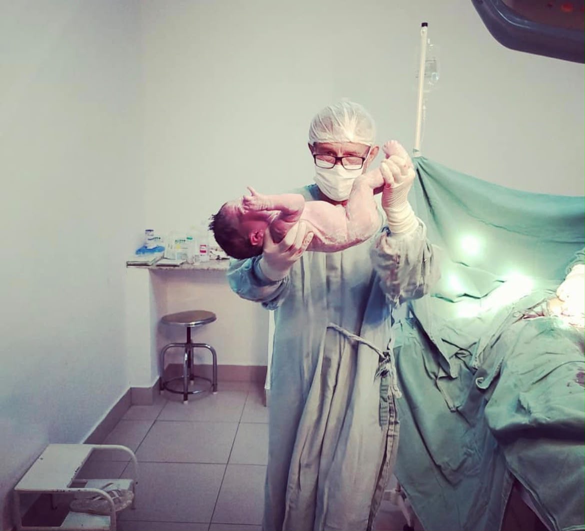 médico segurando bebê recèm nascido.