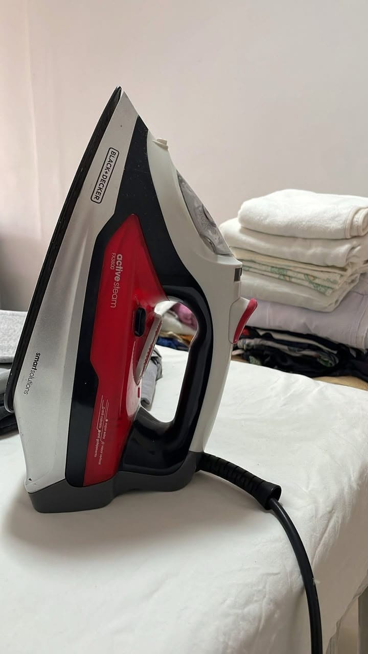 um ferro de passar roupas e muitas roupas de bebê