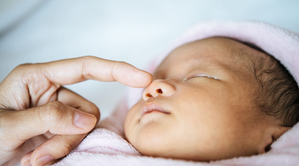A mão da mãe toca o nariz do bebê recém-nascido